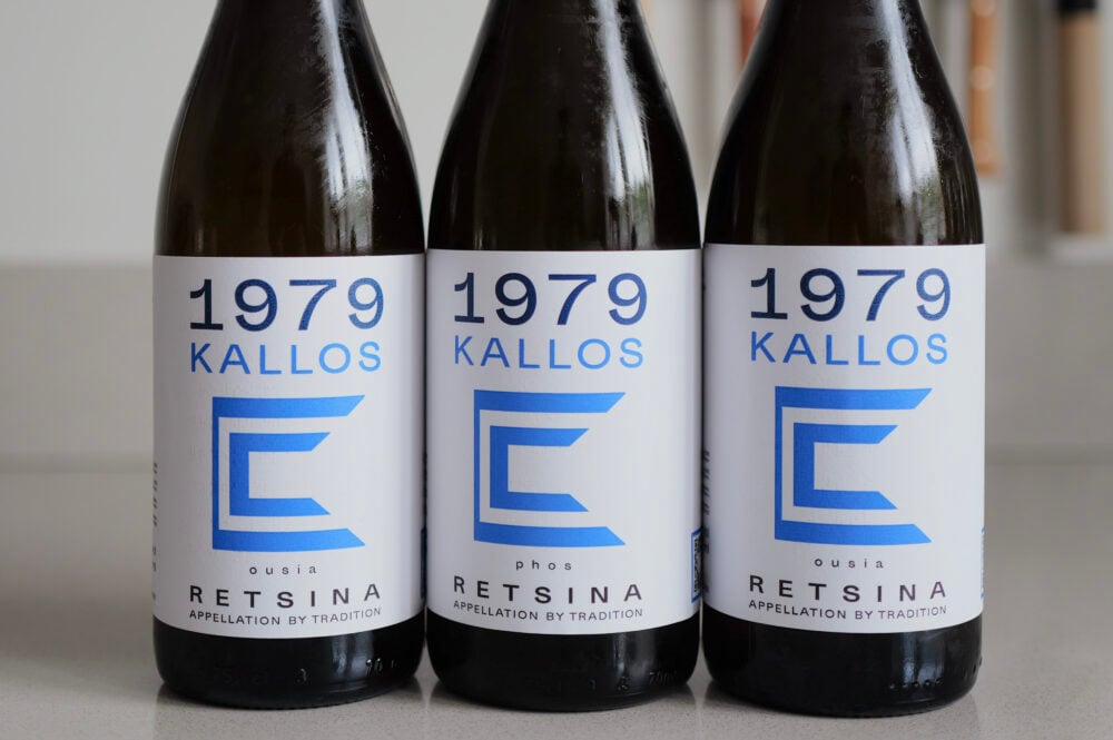 Drie flessen 1979 Kallos Retsina met blauwe etiketten naast elkaar