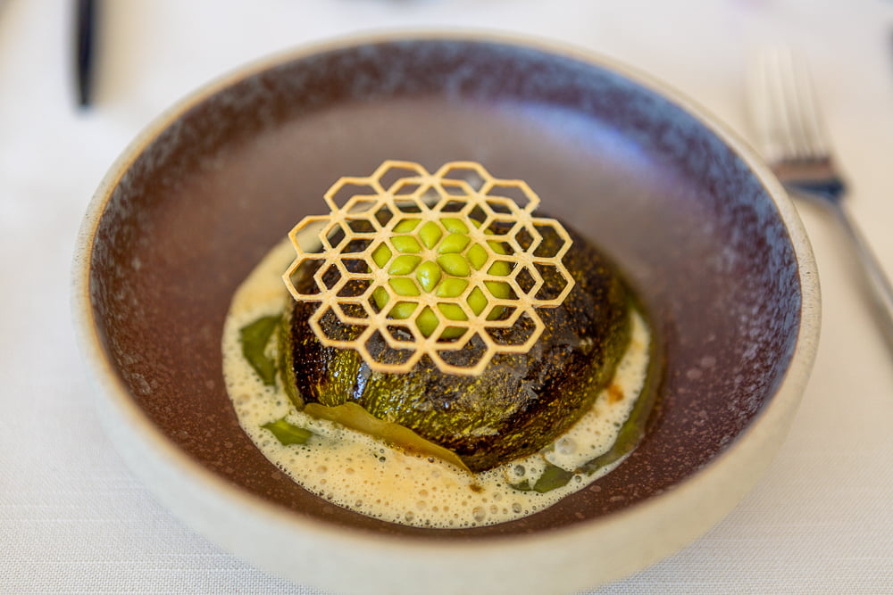 Gevulde courgette met honingraatdecoratie en schuimsaus in keramische kom