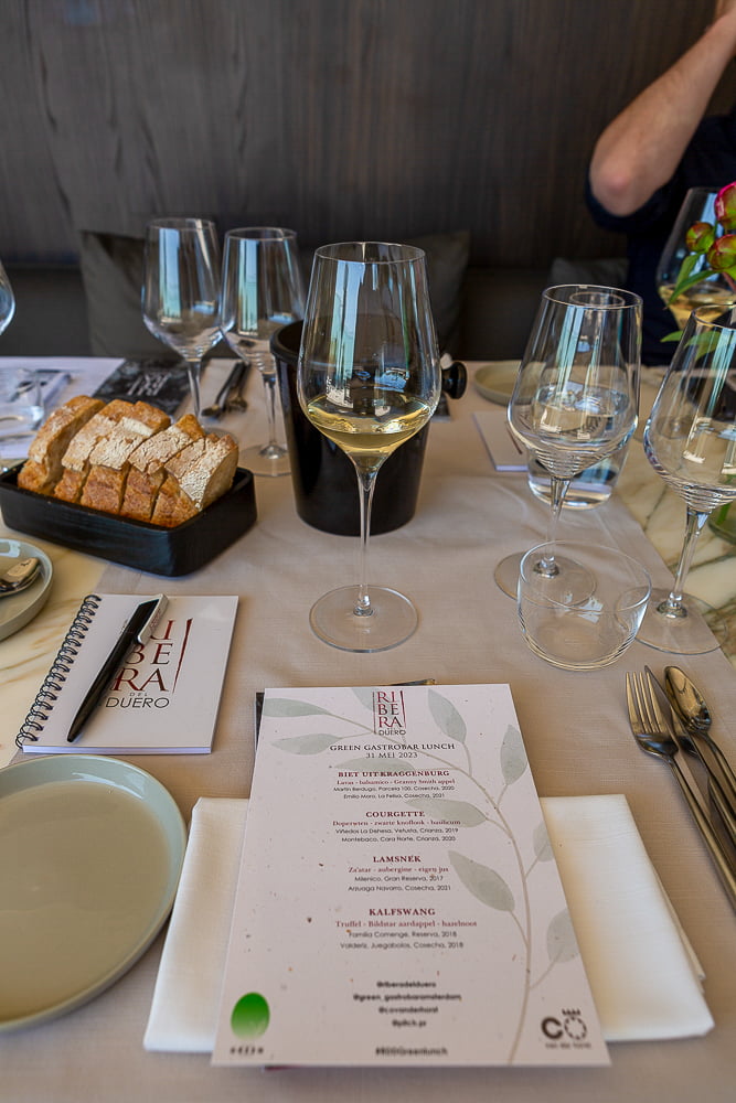 Gedekte tafel met witte wijn, brood en Ribera del Duero menukaart in restaurant