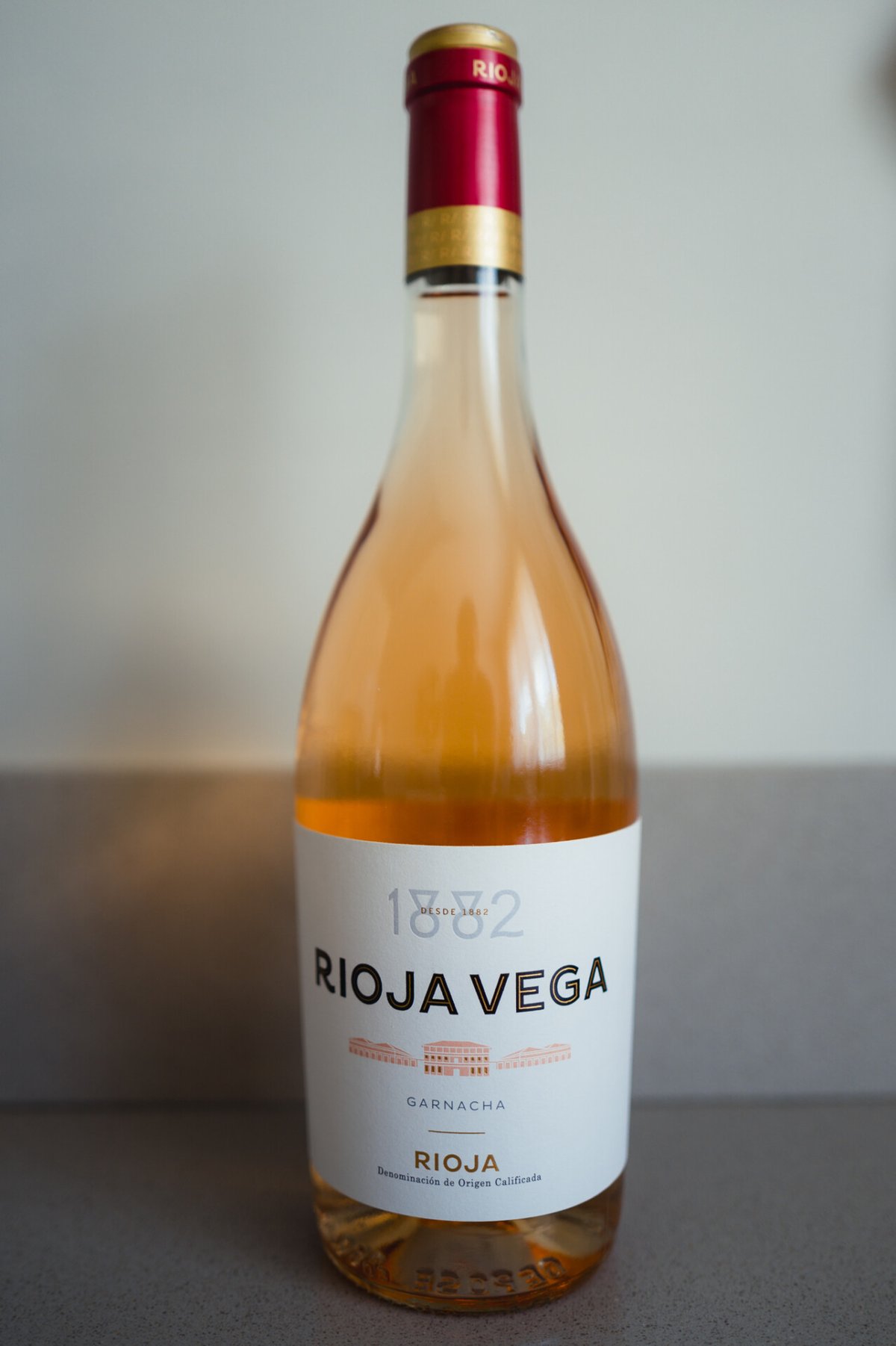Fles Rioja Vega 1882 Rosado Garnacha rechtop voor een neutrale achtergrond
