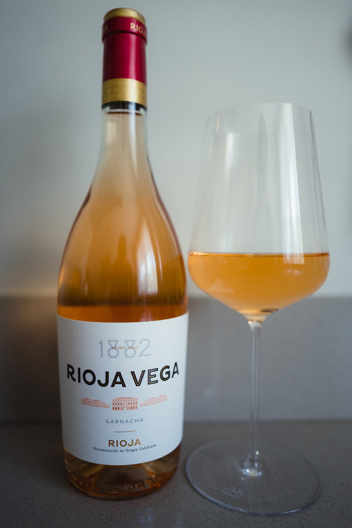 Glas lichtroze Rioja Vega Rosado naast de fles op tafel