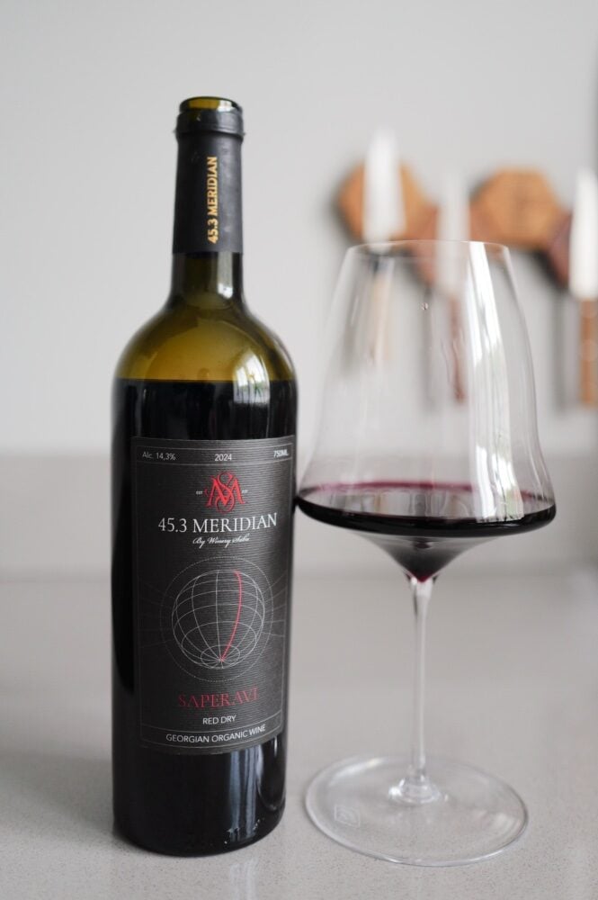 Fles Saperavi 2024 van Winery Saba met een glas donkere rode wijn ervoor
