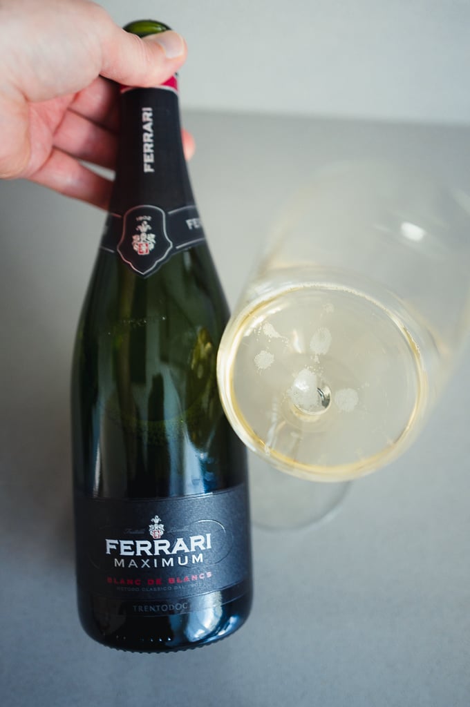 Hand met een gekanteld glas mousserende Ferrari Maximum Blanc de Blancs