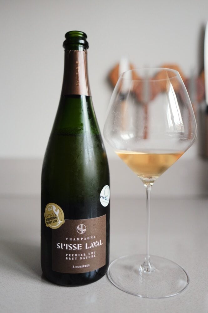 Fles Suisse Laval Brut Nature champagne met goudmedaille-sticker en een glas