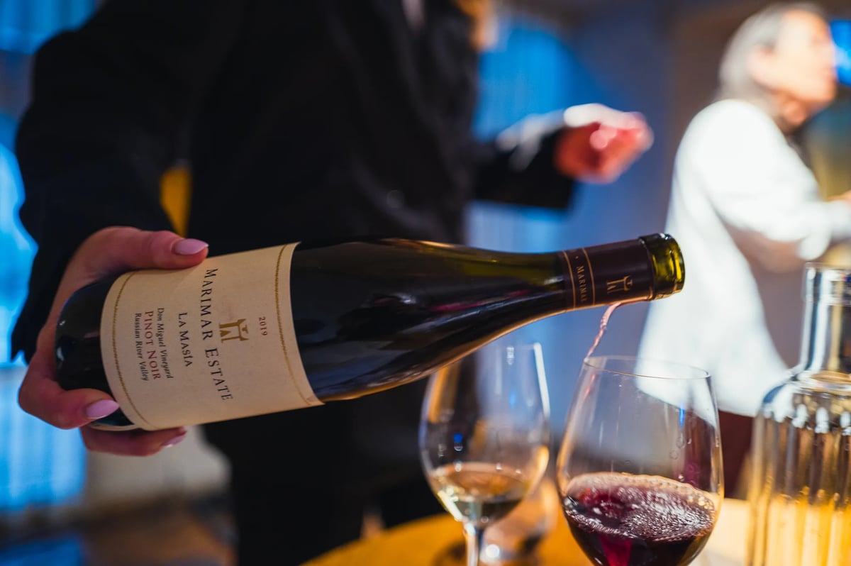 Hand schenkt Marimar Estate Pinot Noir in een glas tijdens het proefevent