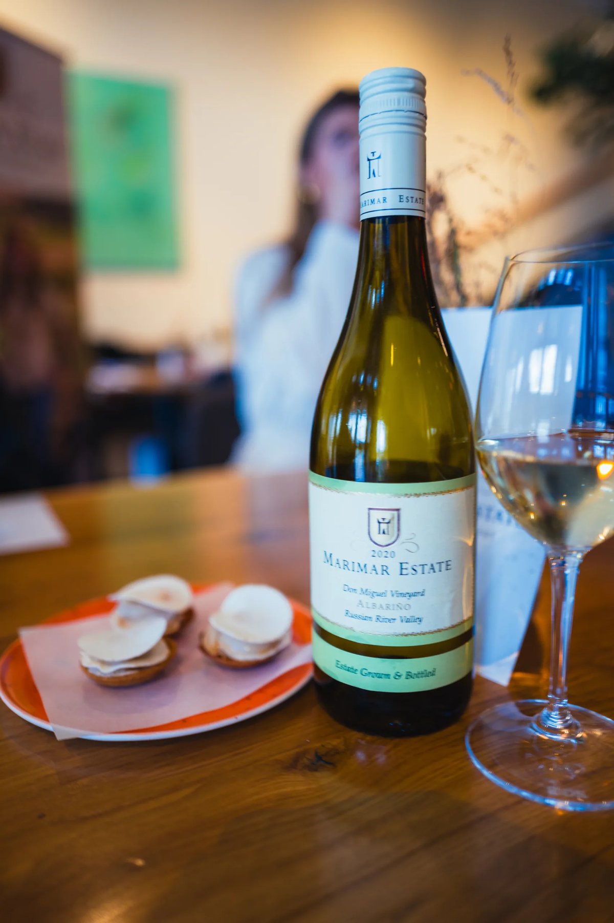 Fles Marimar Estate Albariño 2020 met een glas witte wijn en hapjes op tafel