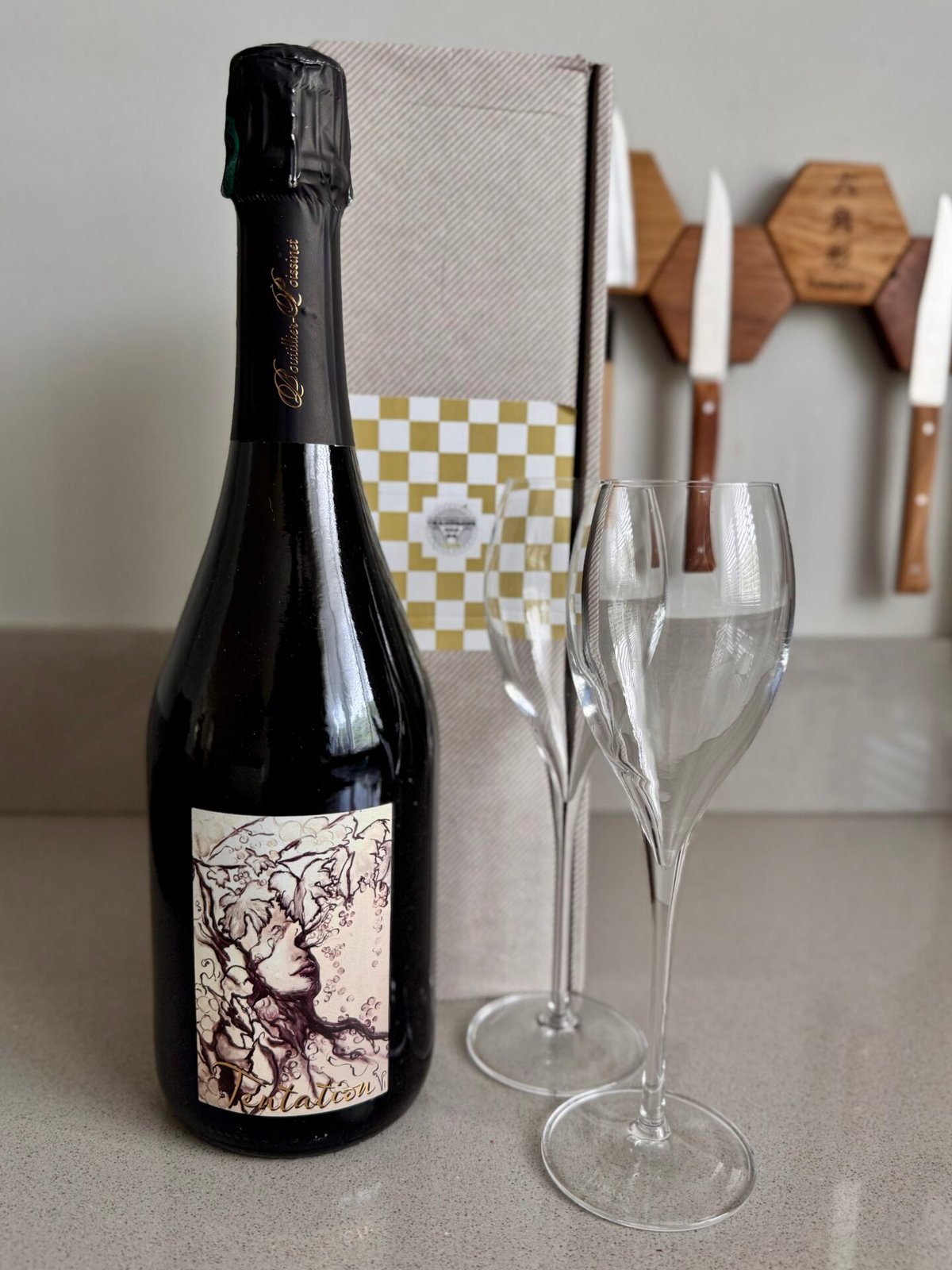 Fles Tentation champagne met een kunstig etiket en twee lege flutes