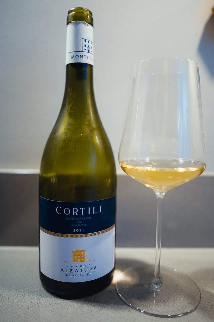 Fles Cortili Montefalco Bianco 2023 met een glas witte wijn ernaast