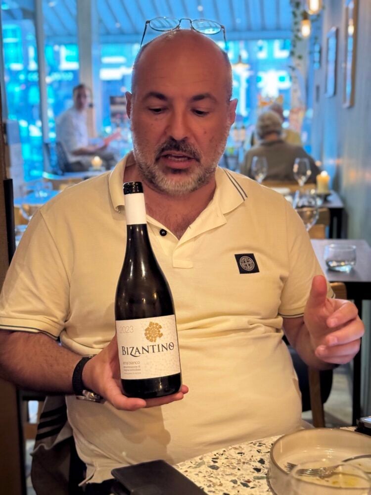 Man in een restaurant toont een fles Bizantino Etna Bianco 2023