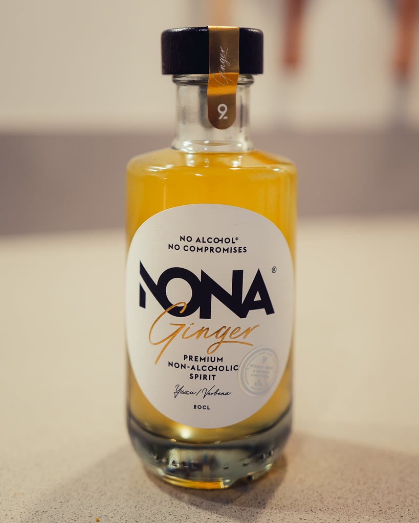 Fles NONA June met een glas heldere drank op ijs, klaar voor serveren aan tafel