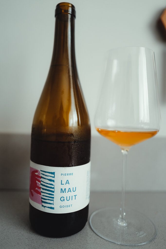 Fles Pierre Goiset La Mauguit met een wijnglas gevuld met amberkleurige Melon de Bourgogne