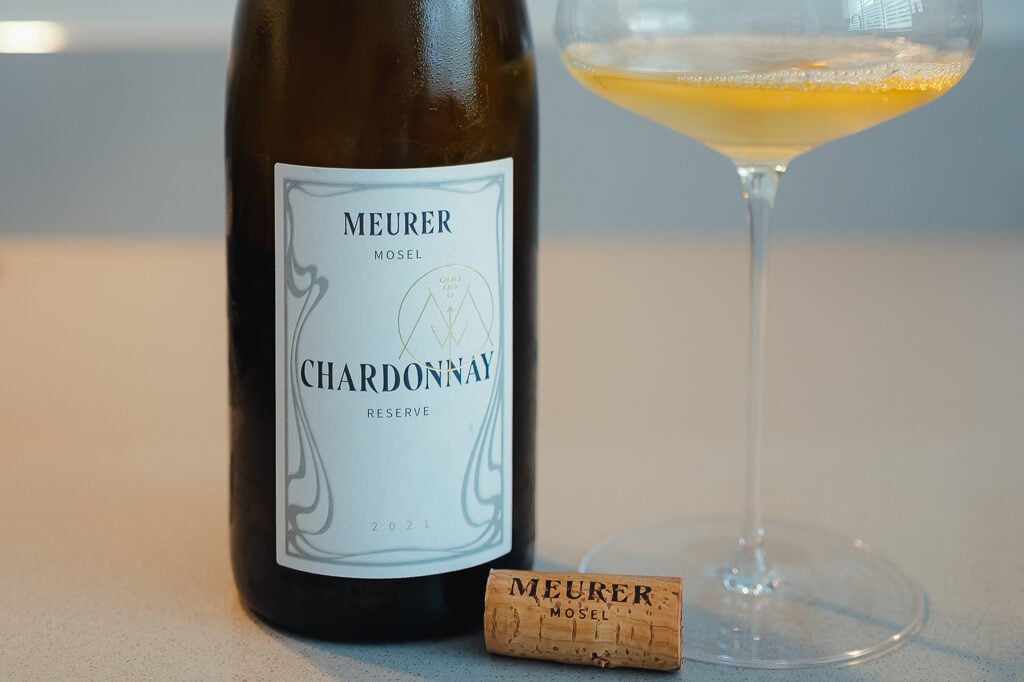 Fles Meurer Chardonnay Reserve uit de Mosel met kurk en een coupe goudgele wijn