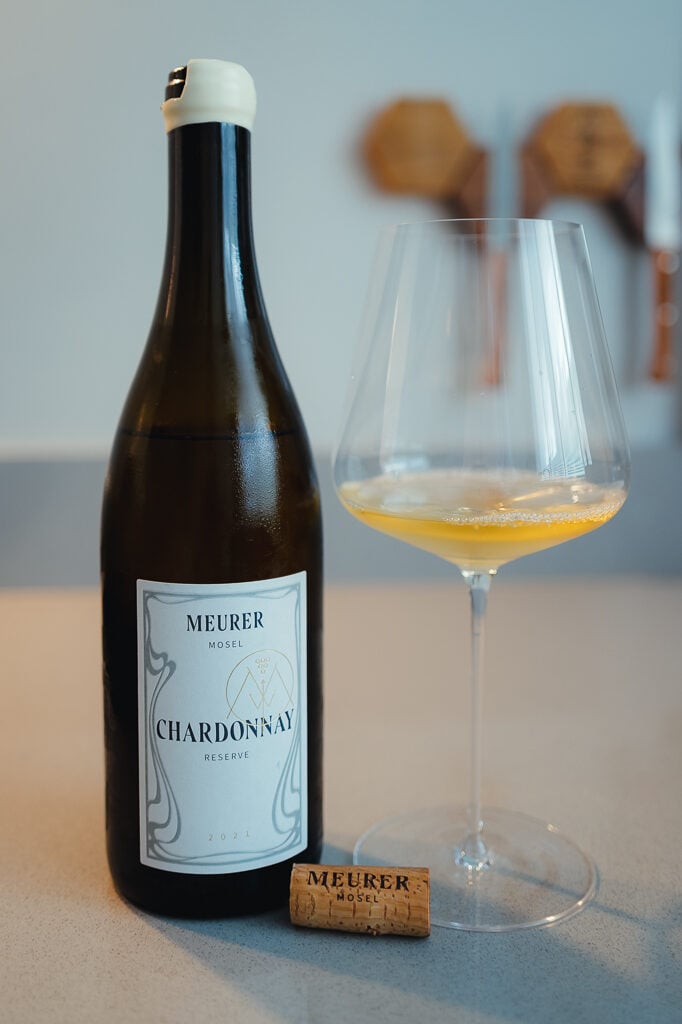 Fles Meurer Chardonnay Reserve met kurk en een wijnglas met goudgele Chardonnay