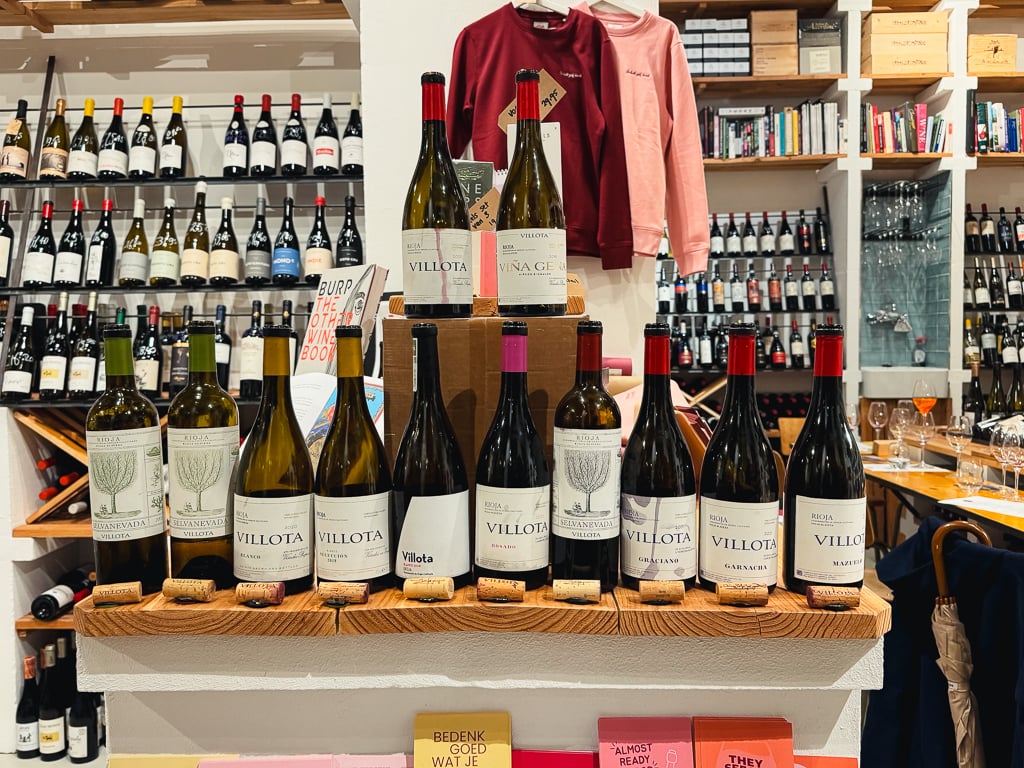 Rij Villota wijnflessen op een houten plank in een wijnwinkel