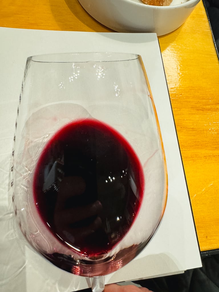 Glas diep robijnrode Villota wijn van bovenaf op een proefkaart