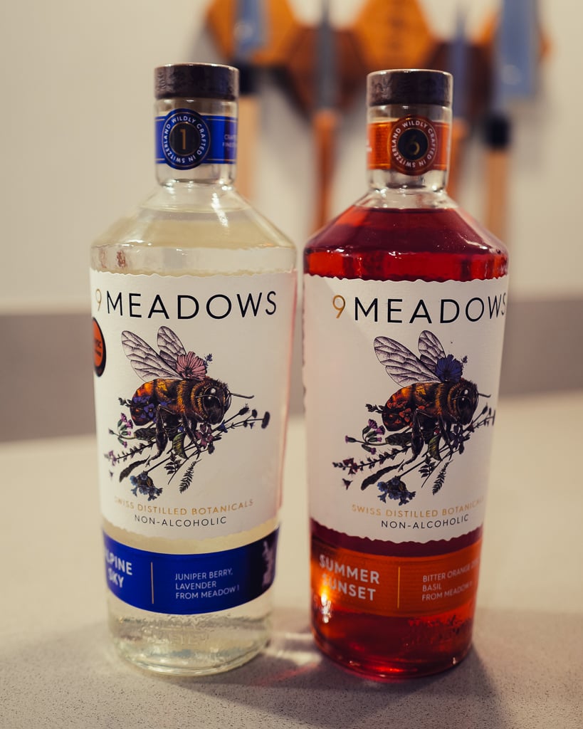 Two 9 Meadows non-alcoholic spirit bottles, clear Alpine Sky and red Summer Sunset