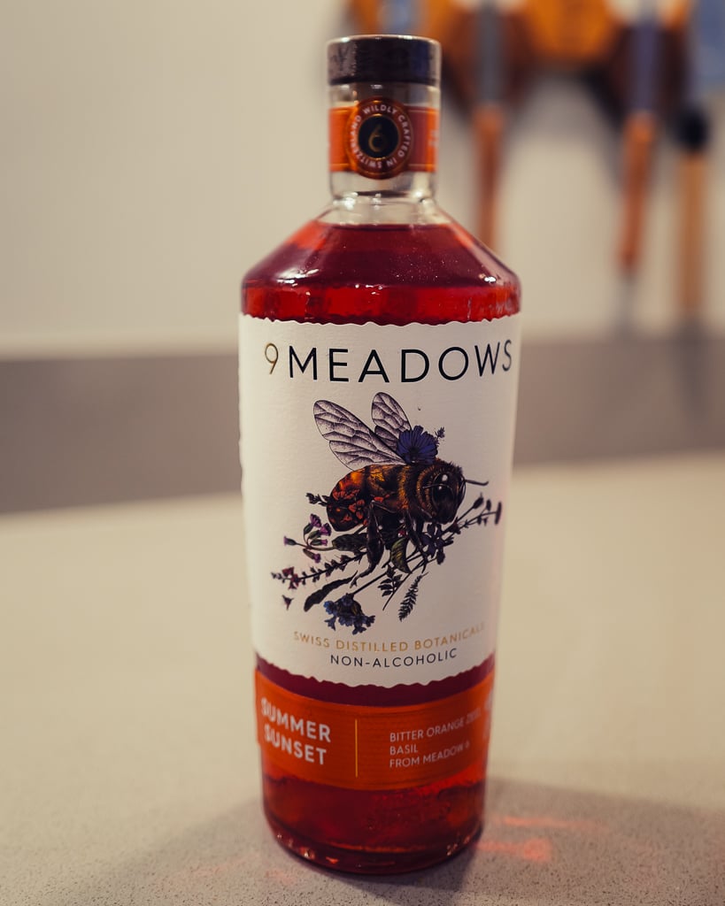 Red-hued Summer Sunset bottle with bee label standing on a counter