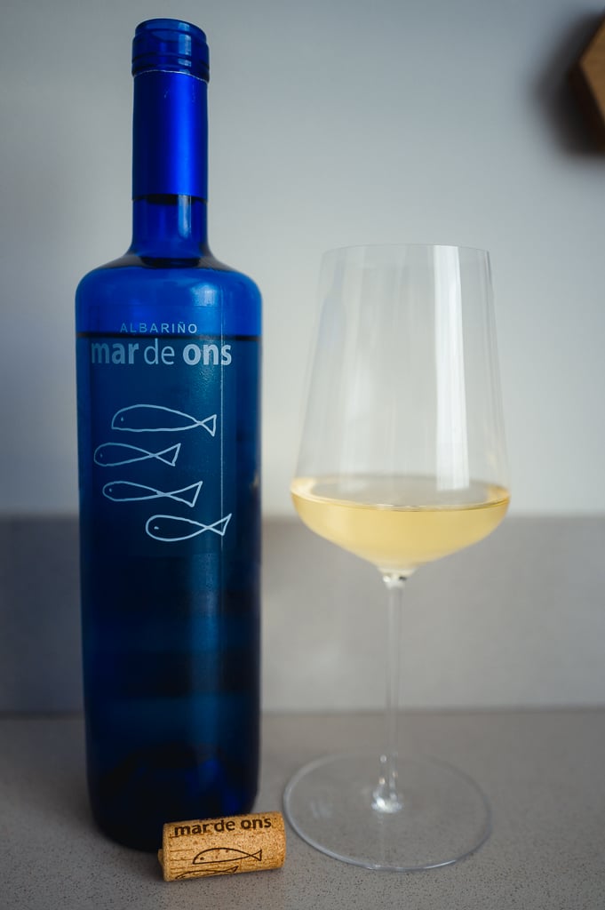 Blauwe fles Mar de Ons Albariño met glas lichtgele wijn en een kurk ervoor