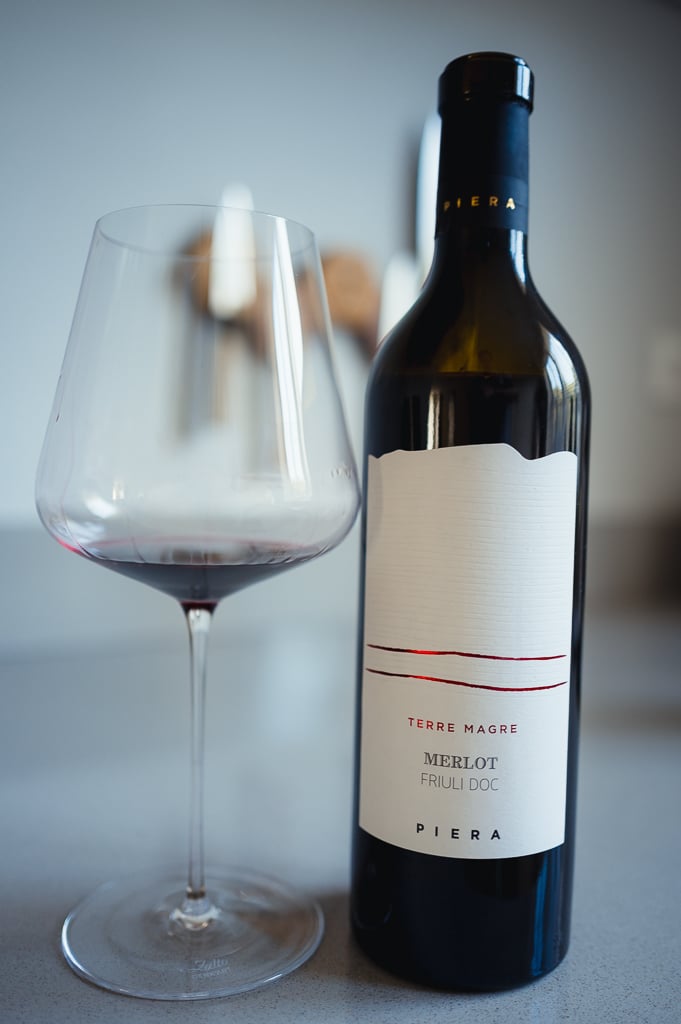 Fles Piera Merlot naast een glas met restje dieprode wijn op een aanrecht