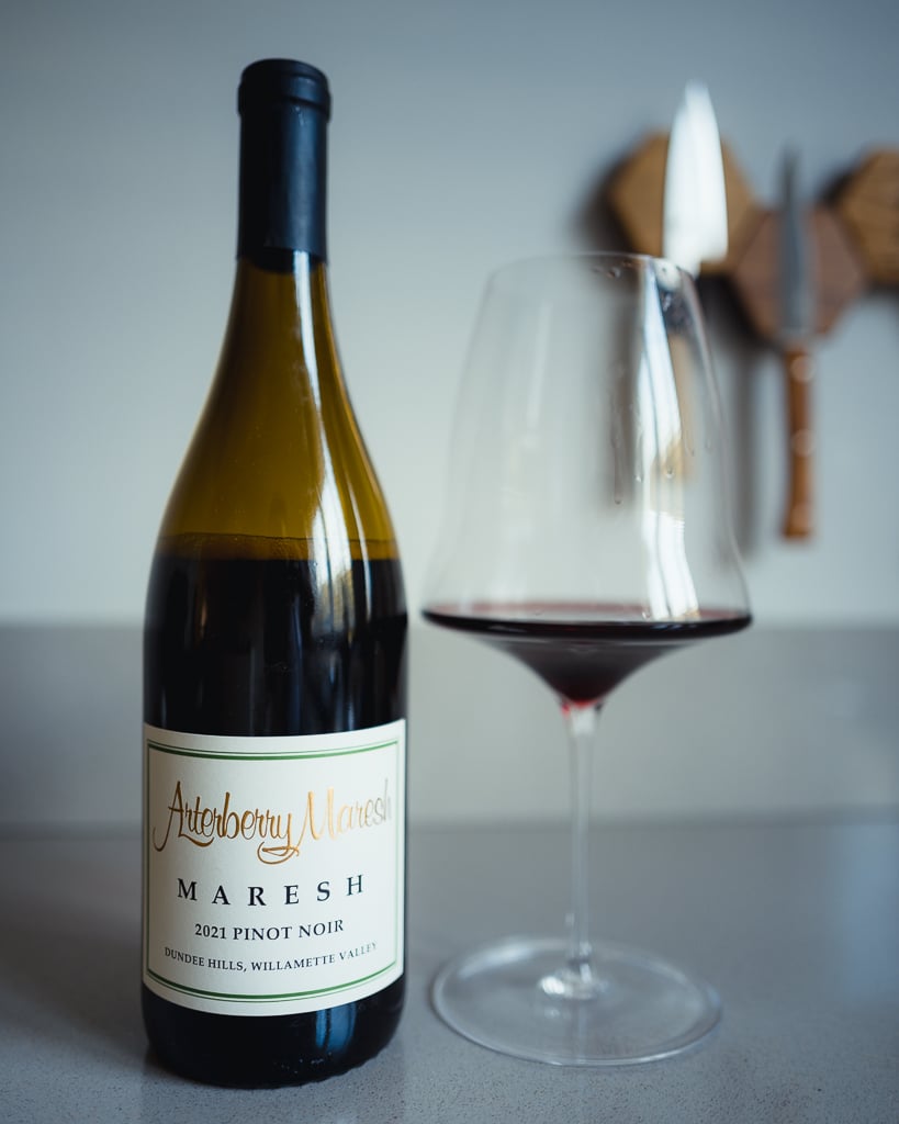 Fles Arterberry Maresh 2021 Pinot Noir naast een glas rode wijn op een aanrecht