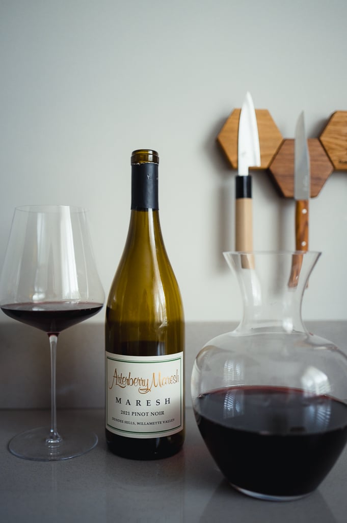 Fles Arterberry Maresh 2021 Pinot Noir naast een glas rode wijn met karaf rode wijn