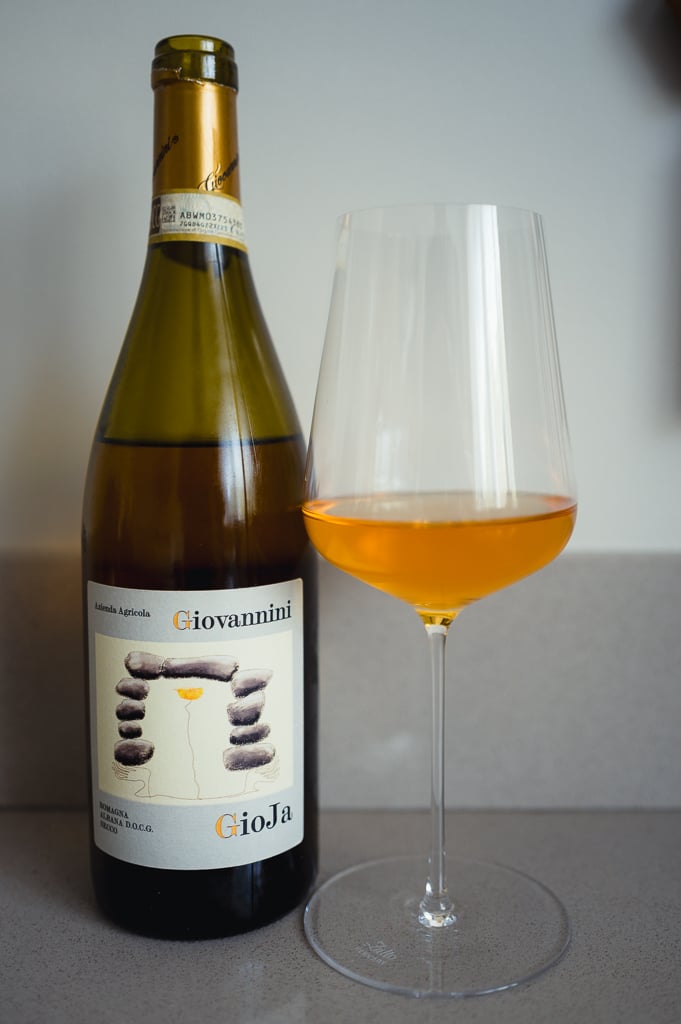 Fles Giovannini GioJa Albana DOCG naast een glas diepgele oranje witte wijn