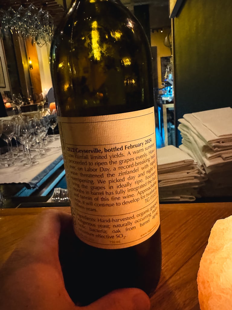 Glas rode wijn voor een raam met uitzicht op een straat in Amsterdam