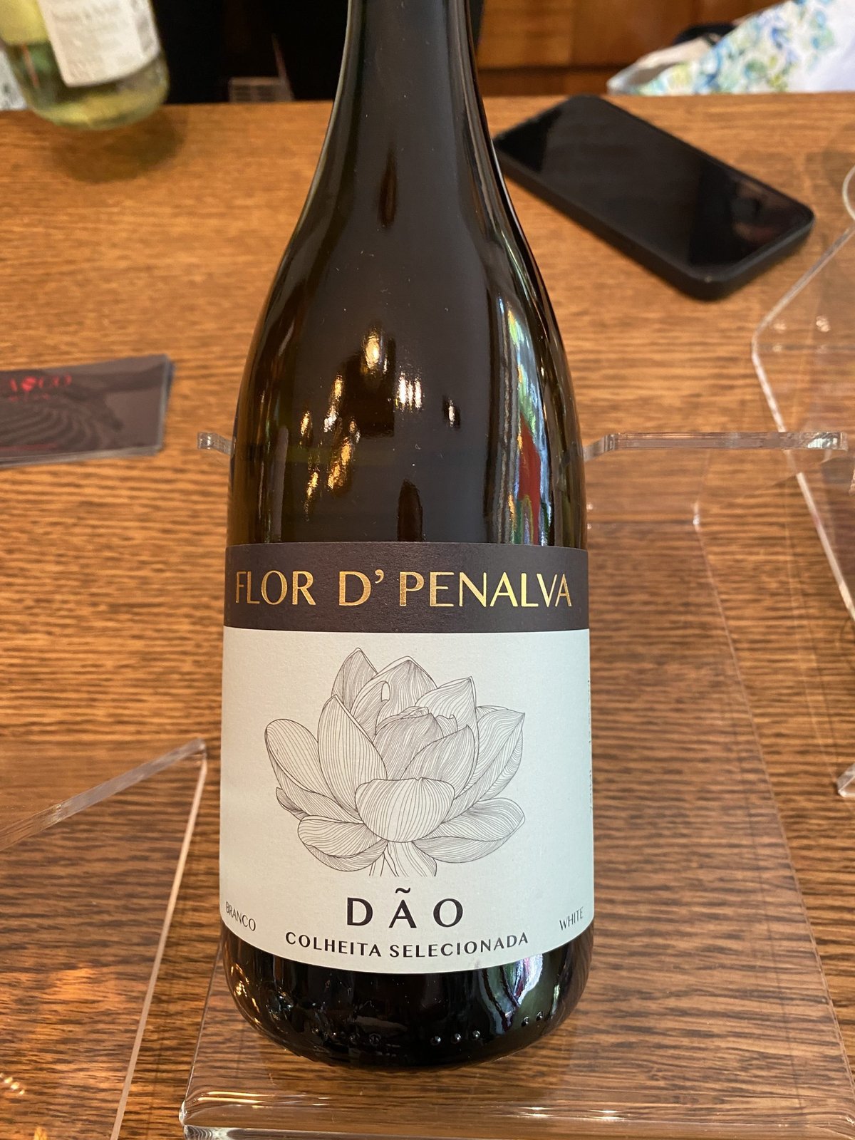 Fles Flor d'Penalva Dão witte wijn met lotusbloem op het etiket op een houten tafel