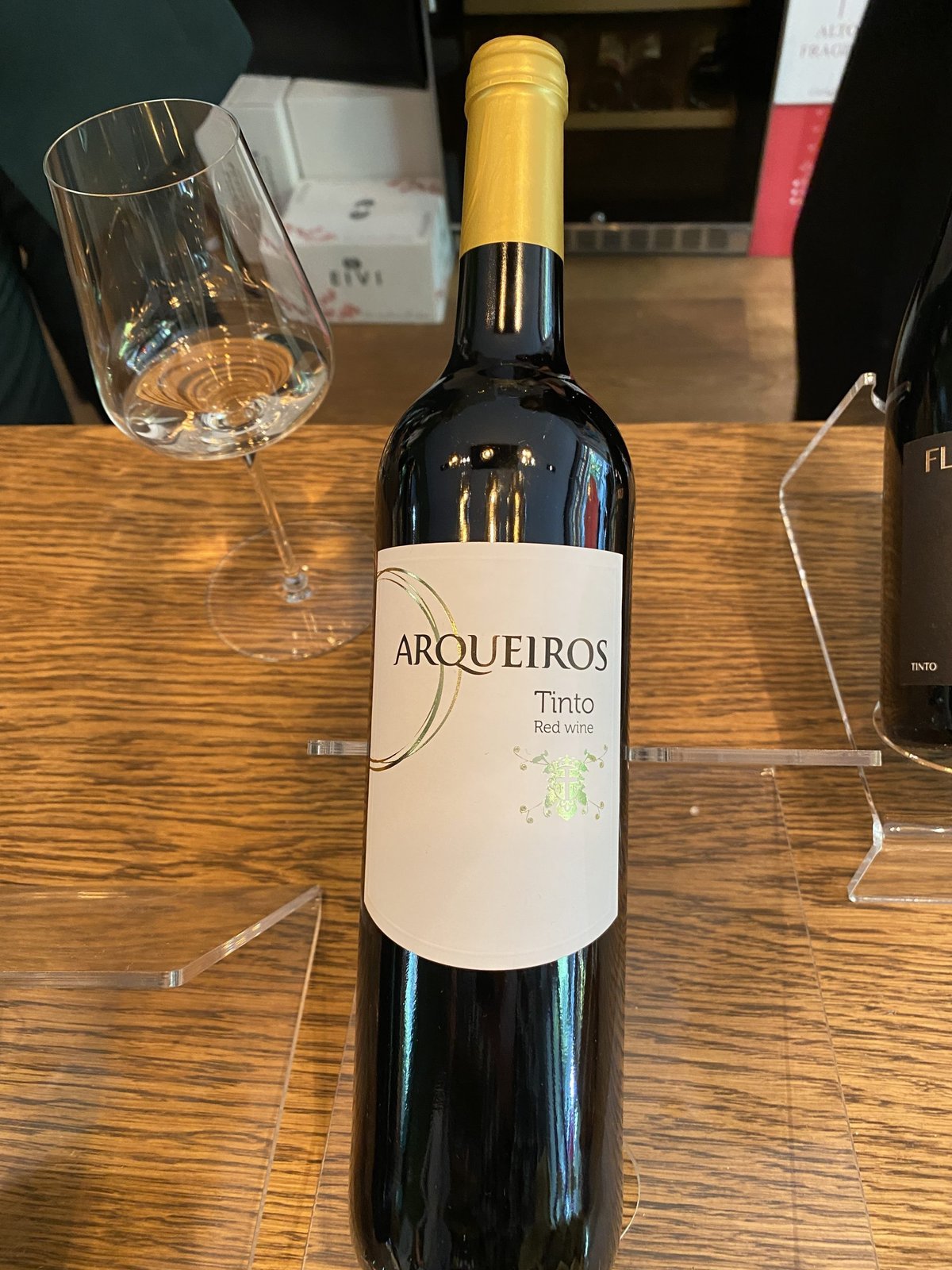 Fles Arqueiros Tinto rode wijn met geel folie naast een leeg wijnglas
