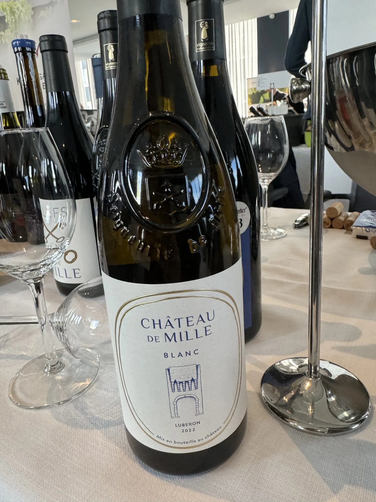 Fles Château de Mille Blanc Luberon op een proeftafel tussen andere flessen