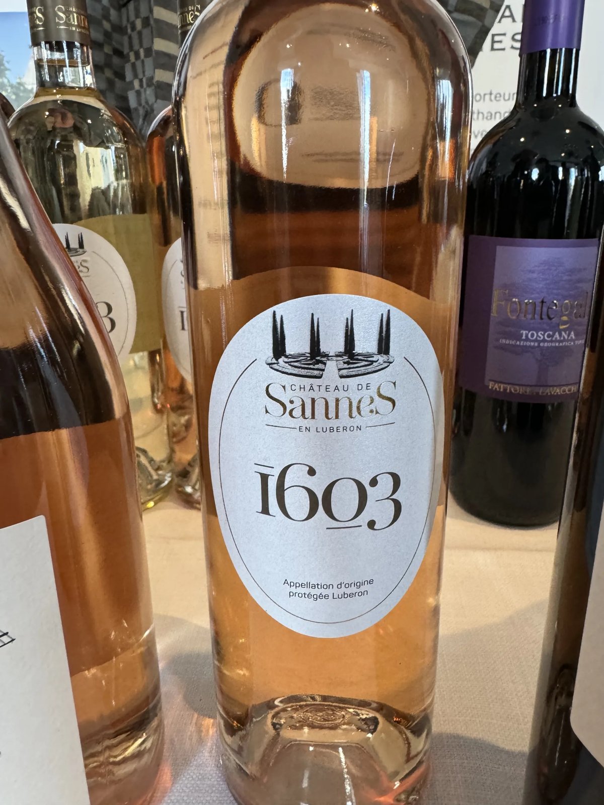 Fles Château de Sannes 1603 rosé met cipressen op het etiket tussen andere flessen