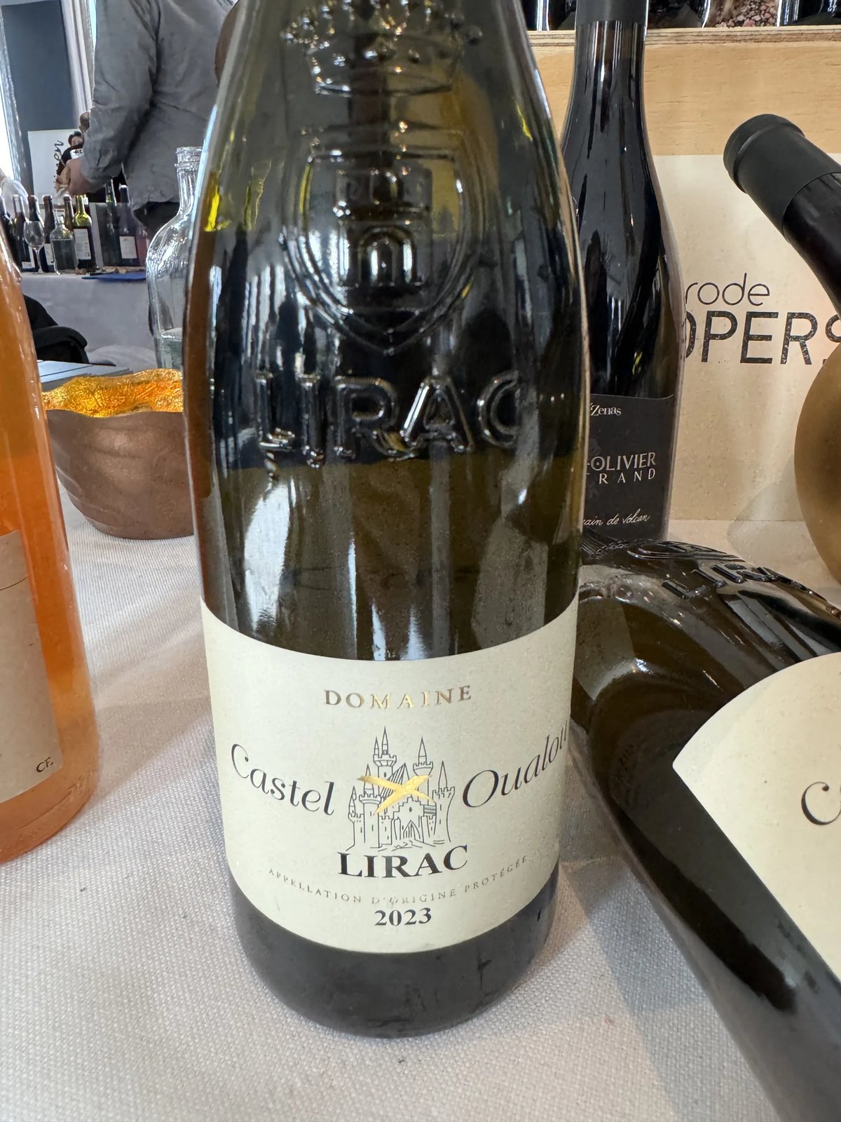 Fles Castel Oualou Lirac witte wijn met kasteelillustratie op een proeftafel
