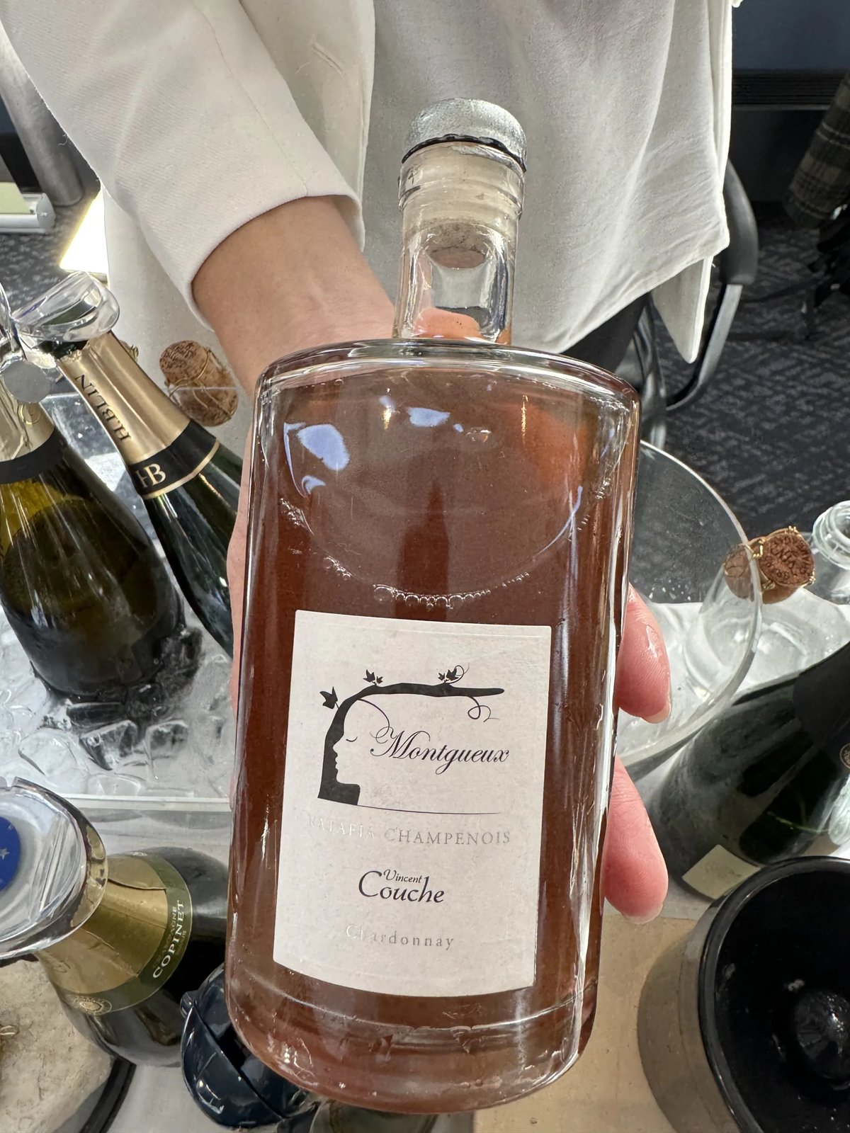 Hand houdt karaf-vormige fles Vincent Couche Montgueux roze drank vast