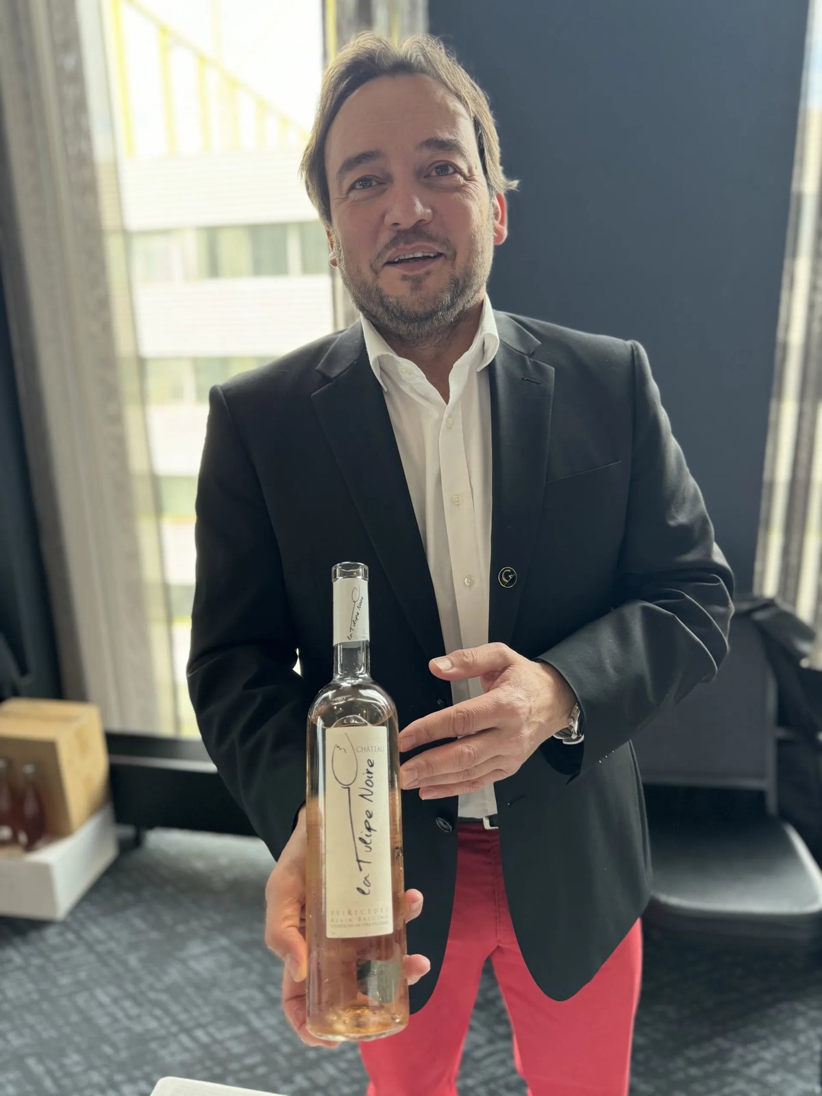 Fles Chelou oranje wijn op een proefstand met champagne-affiche op de achtergrond