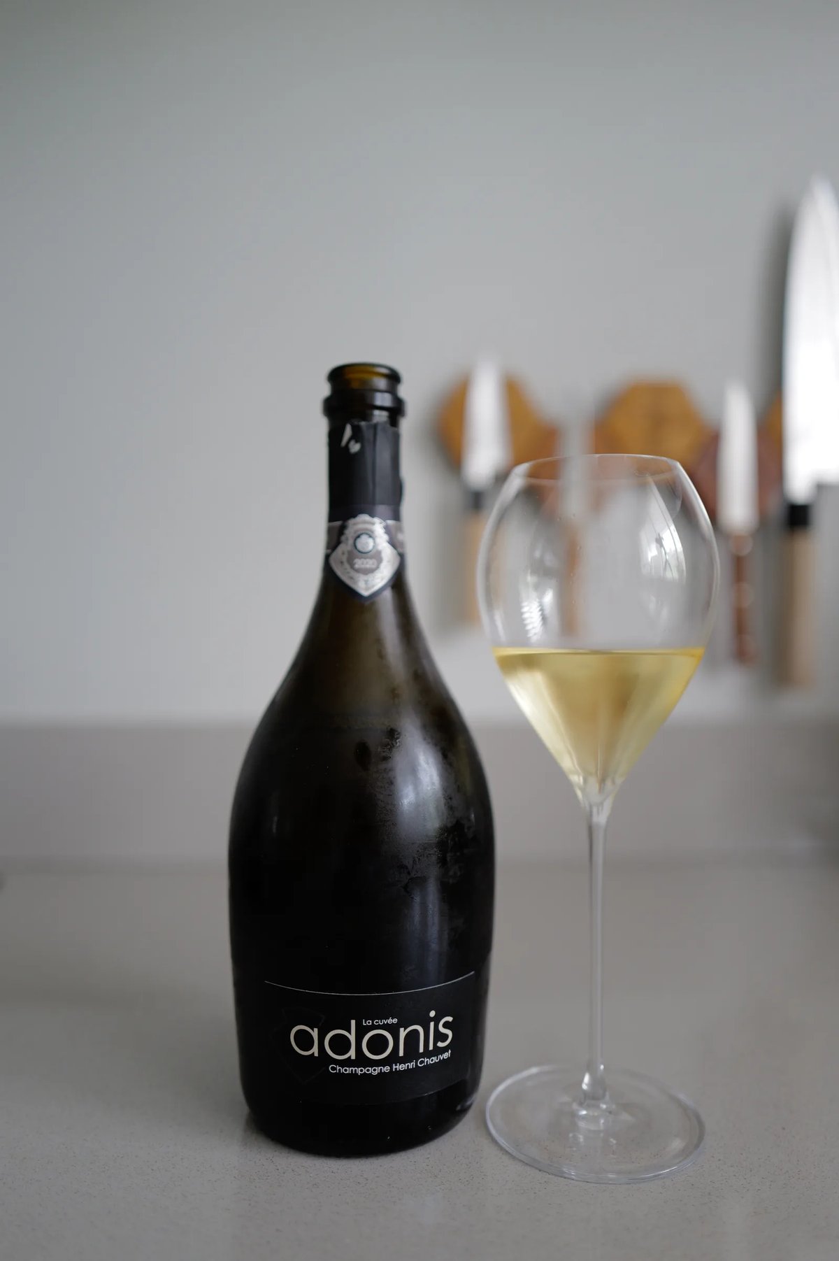 Fles Henri Chauvet Adonis 2020 naast een glas champagne