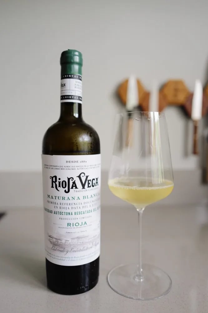 Fles Rioja Vega Maturana Blanca 2025 met vooretiket naast een glas bleekgoudgele wijn op een keukenblad