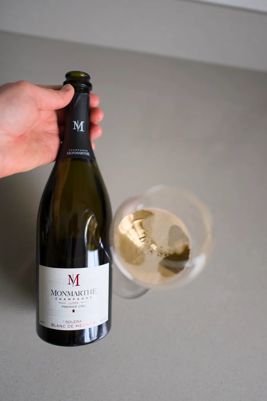 Hand met een fles Champagne Monmarthe Solera Blanc de Meunier