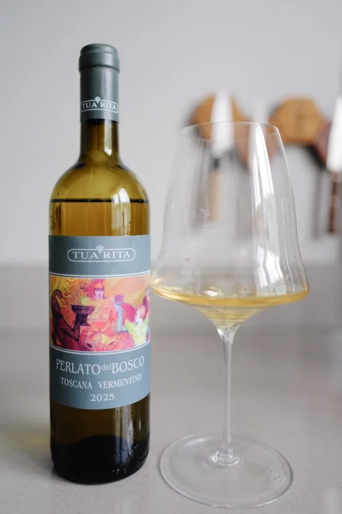 Fles Tua Rita Perlato del Bosco Vermentino 2025 naast een gevuld glas witte wijn