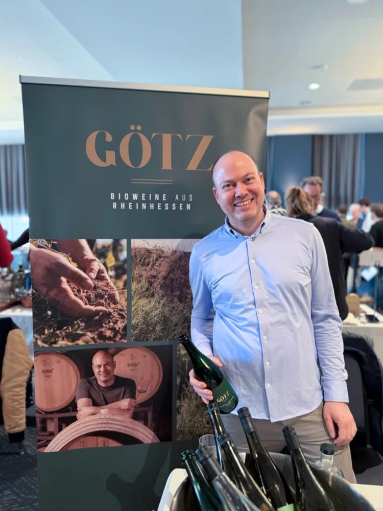 Holger Götz portret met fles voor de Weingut Götz-banner