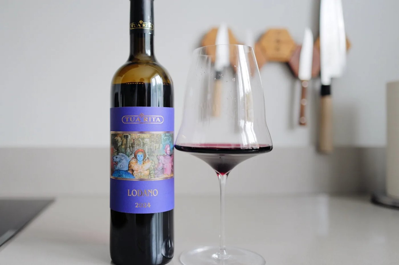 Bottle of Tua Rita Lodano 2024 beside a glass of red wine on a kitchen counter