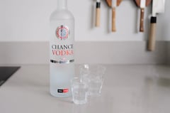 Fles Chance Vodka met roulettelogo naast twee glazen op het aanrecht