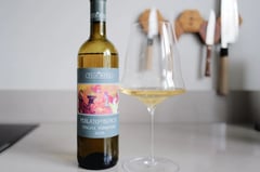 Fles Tua Rita Perlato del Bosco Toscana Vermentino 2025 naast een glas witte wijn op het aanrecht