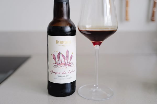 Fles Barbadillo Jopo de Lobo Pedro Ximénez naast een glas donkerrode PX