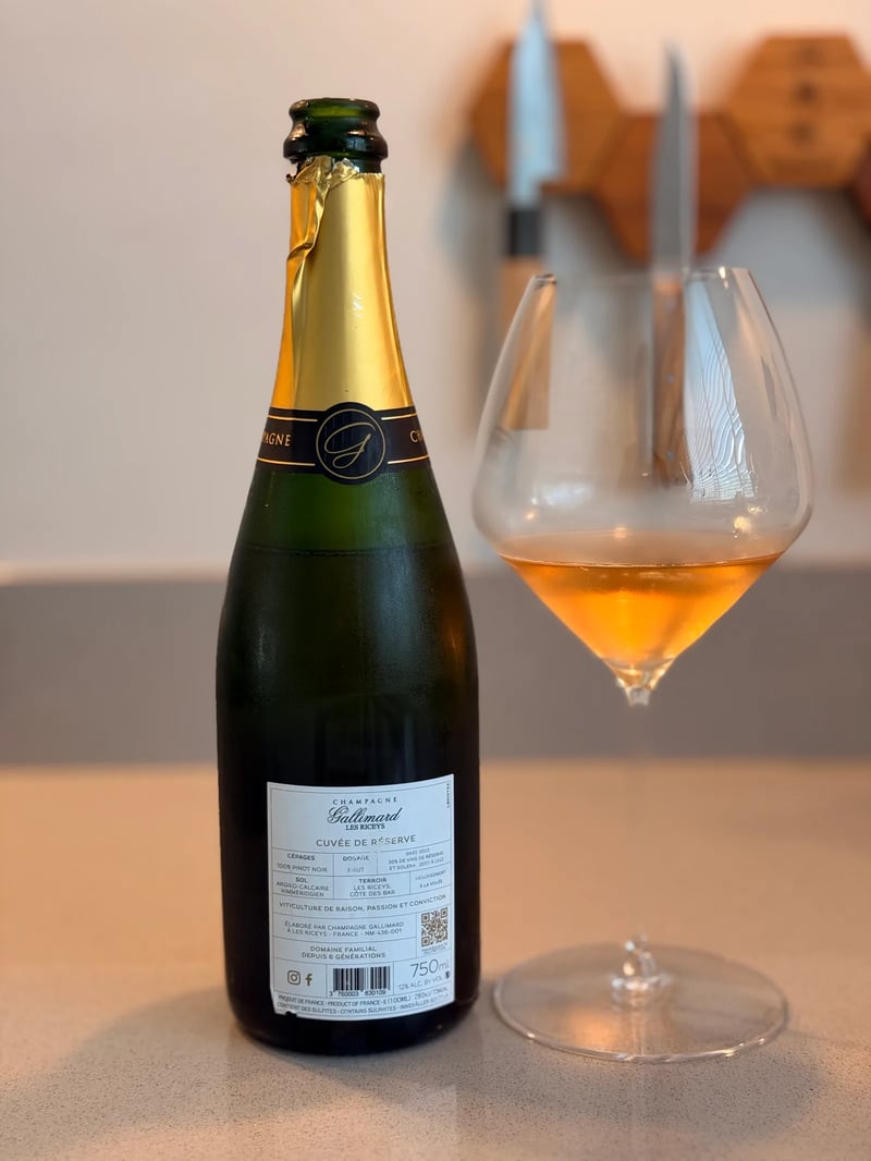Achteretiket Gallimard Cuvée de Réserve Blanc de Noirs naast een glas koperkleurige champagne