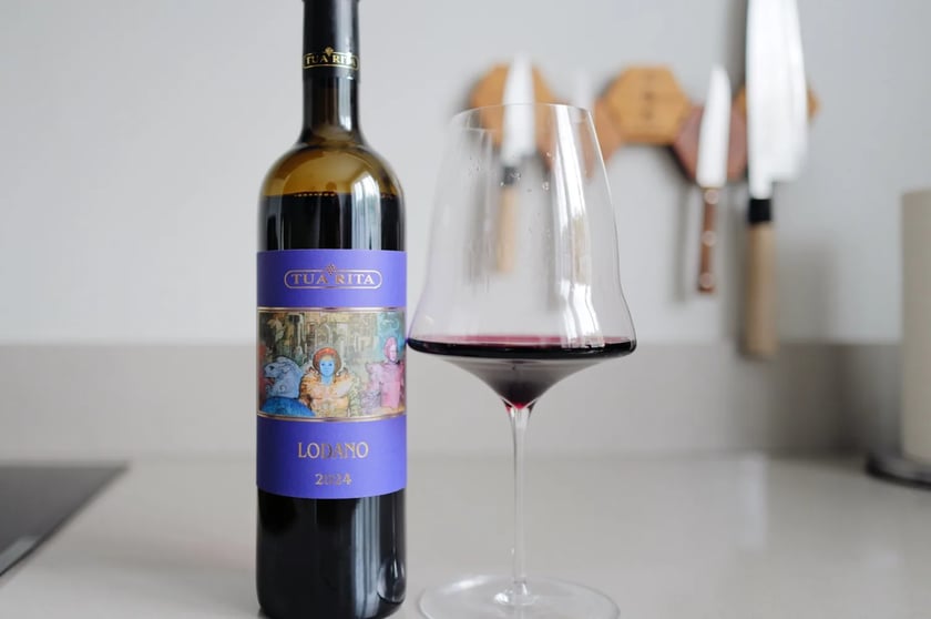 Bottle of Tua Rita Lodano 2024 beside a glass of red wine on a kitchen counter