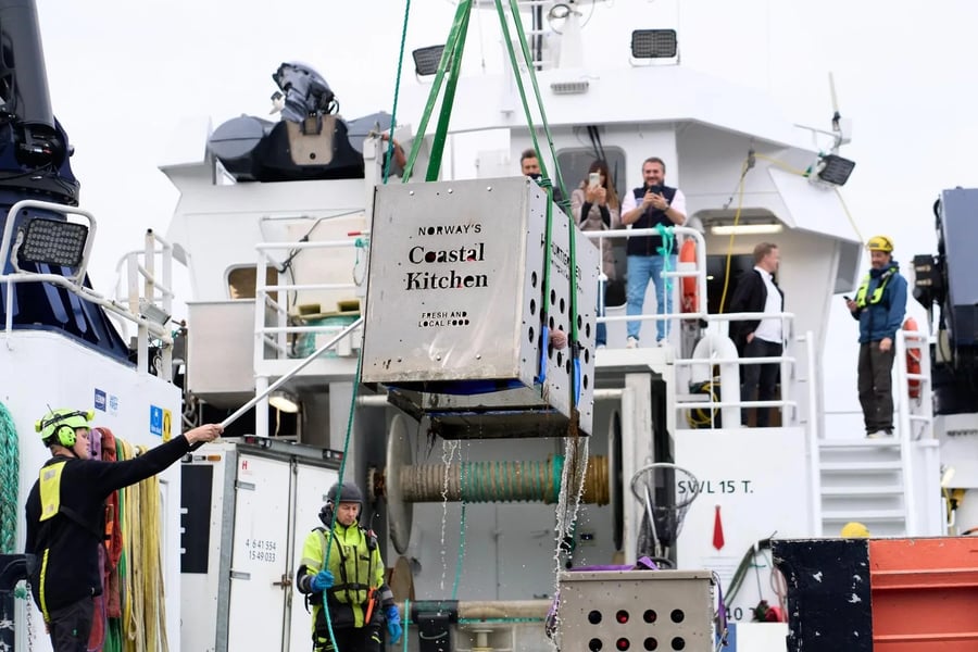 Een stalen kooi met flessen Arctic Barolo wordt bij Kirkenes uit zee aan boord van een schip gehesen