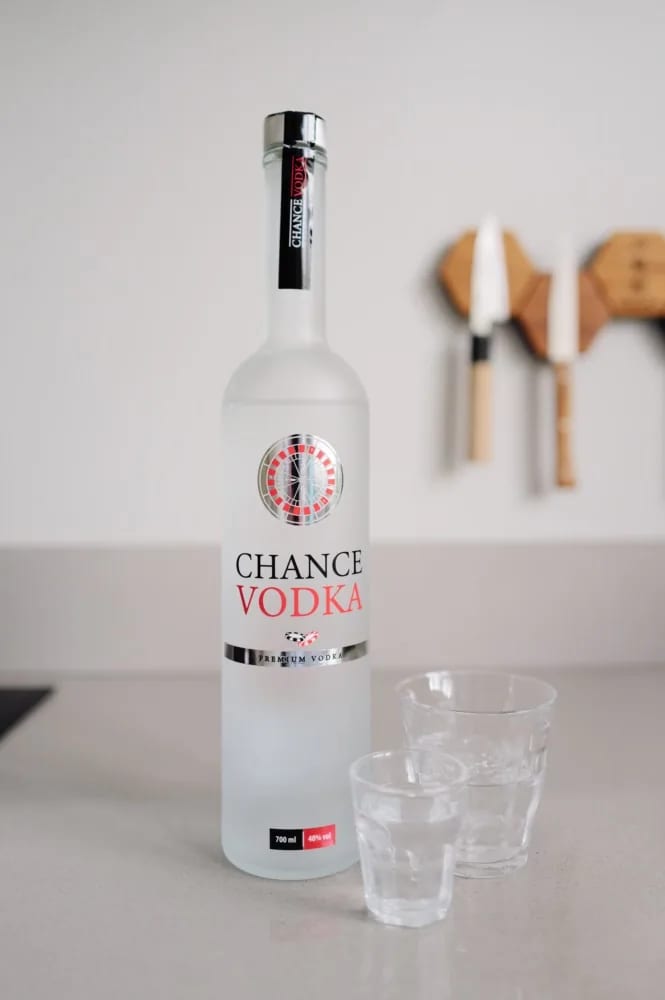 Fles Chance Vodka met roulettelogo naast twee glazen op het aanrecht
