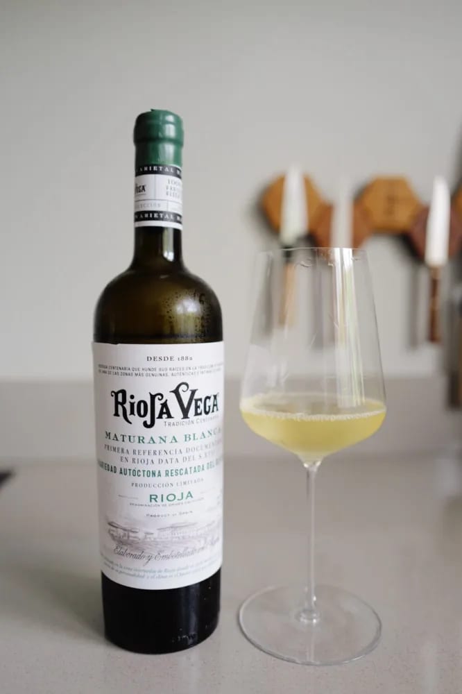 Fles Rioja Vega Maturana Blanca 2025 met vooretiket naast een glas bleekgoudgele wijn op een keukenblad