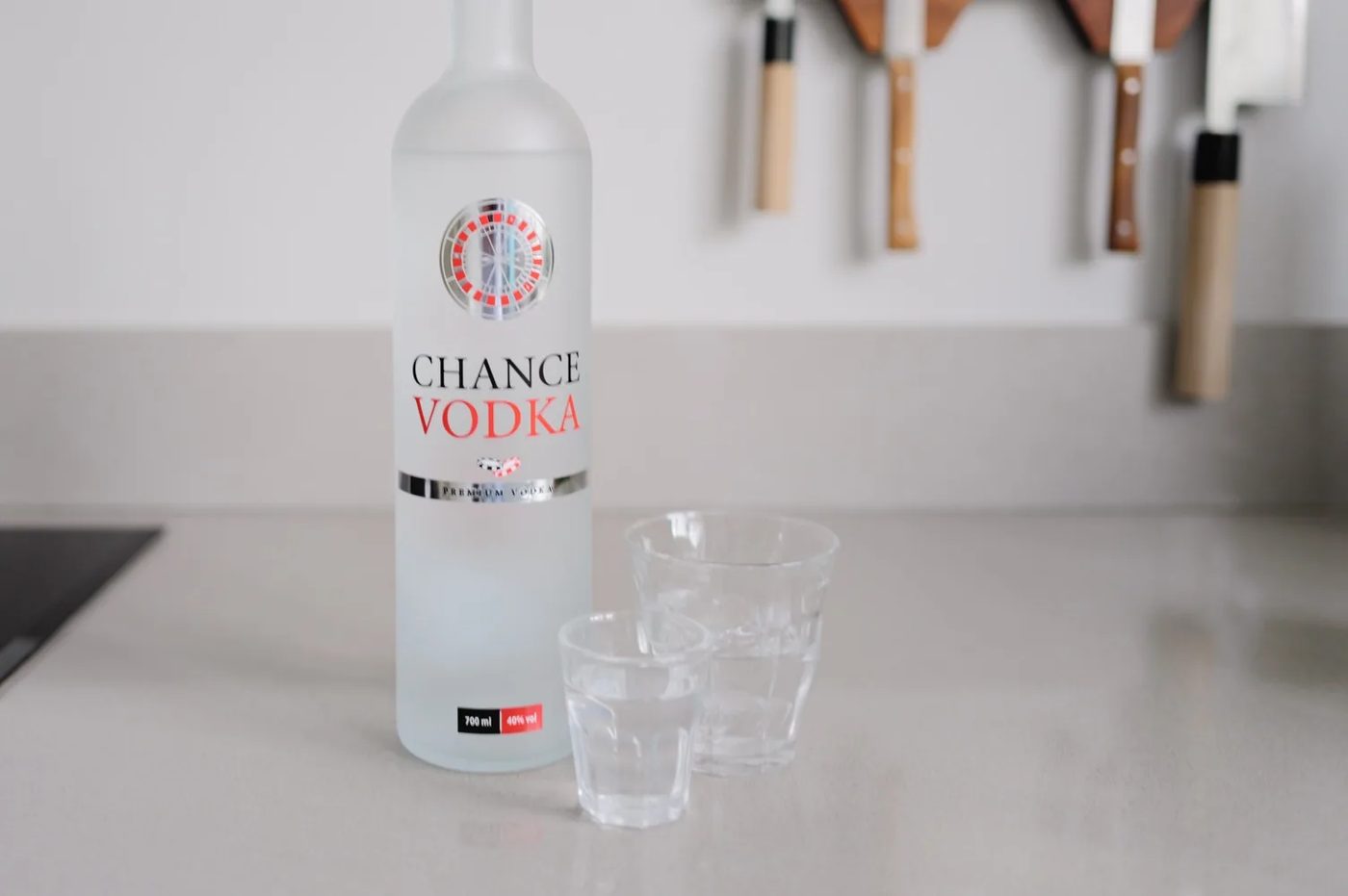 Fles Chance Vodka met roulettelogo naast twee glazen op het aanrecht