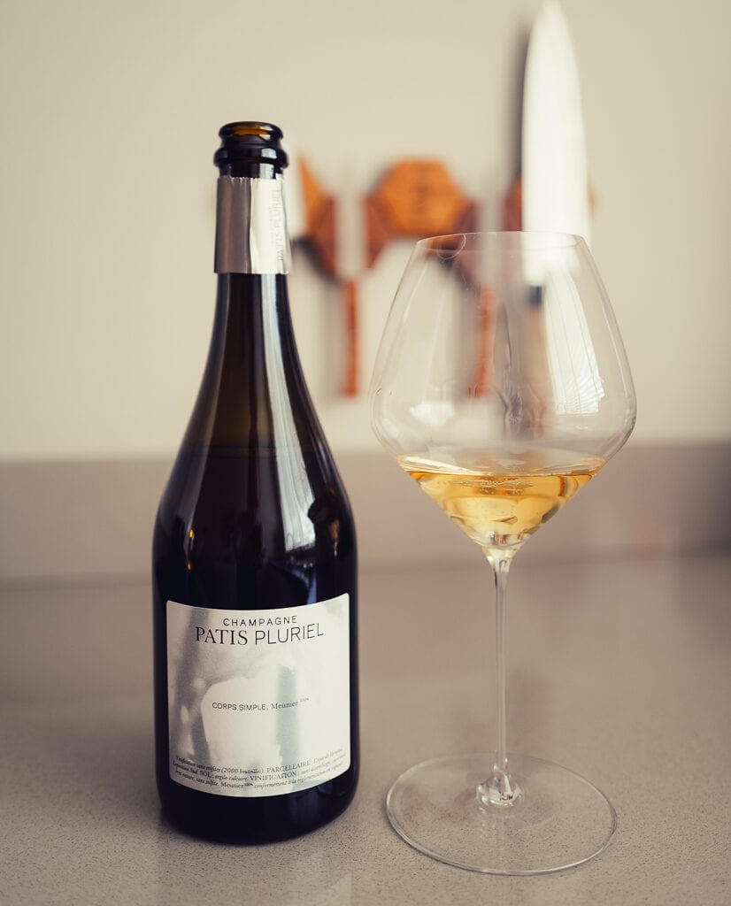 Fles Les Sèves champagne van Patis Pluriel naast een gevuld glas